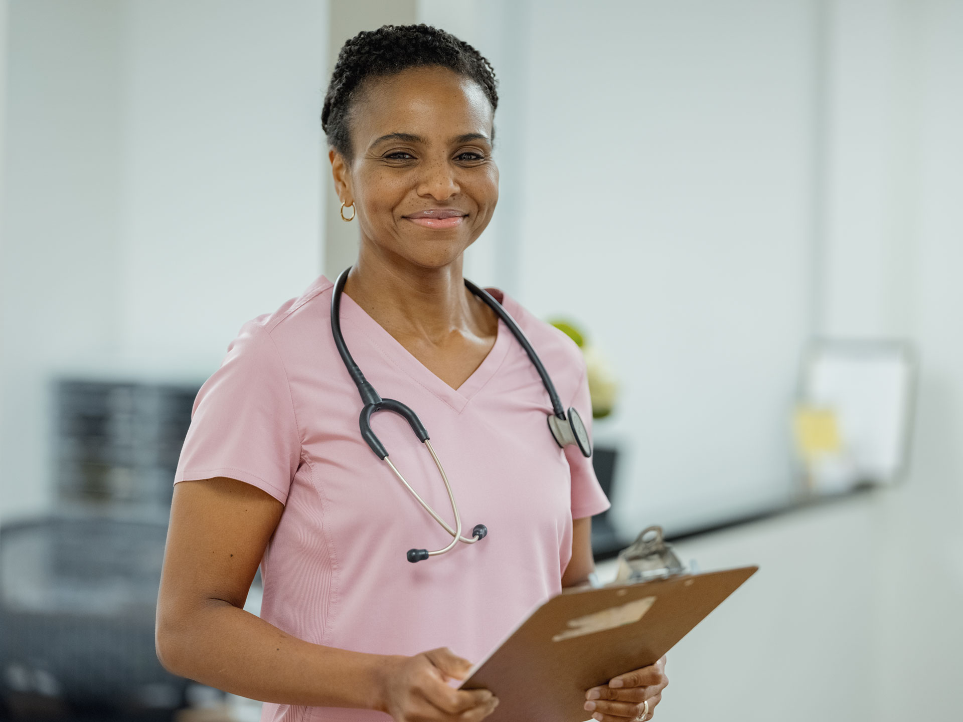 A smiling nurse holding a clipboard